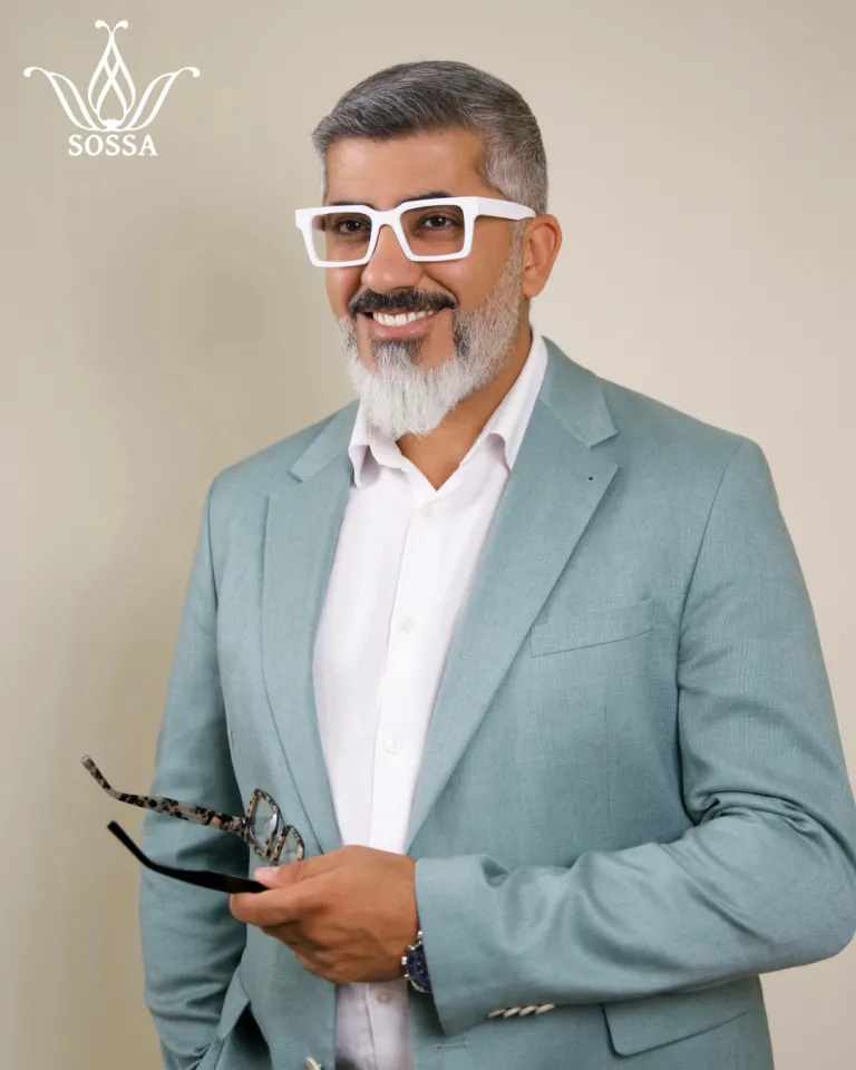 Ali Kemal in a mint blazer wearing white SOSSA frames and holding a second pair